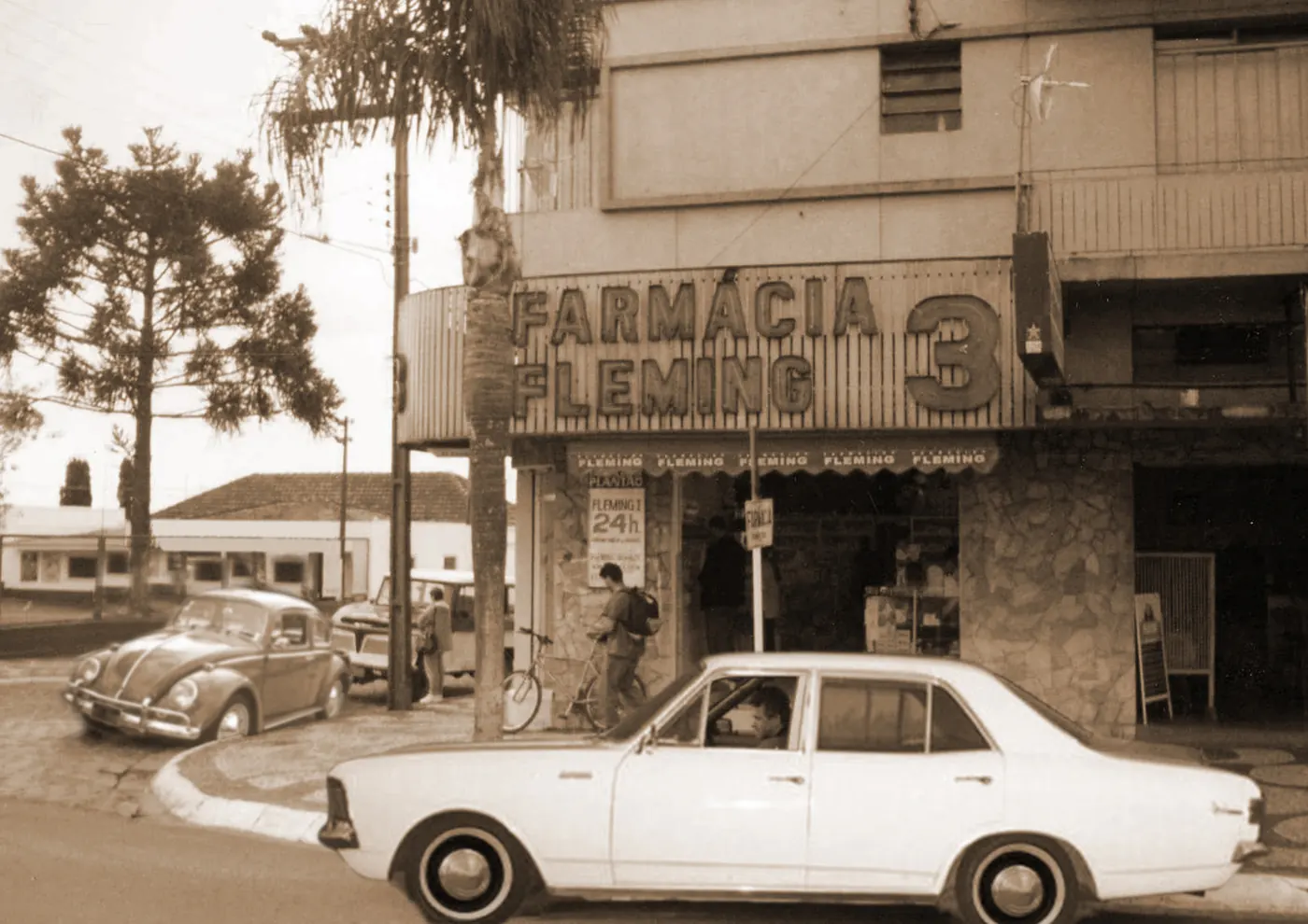 Farmácia Fleming número 3 em foto antiga, com carros da época na rua