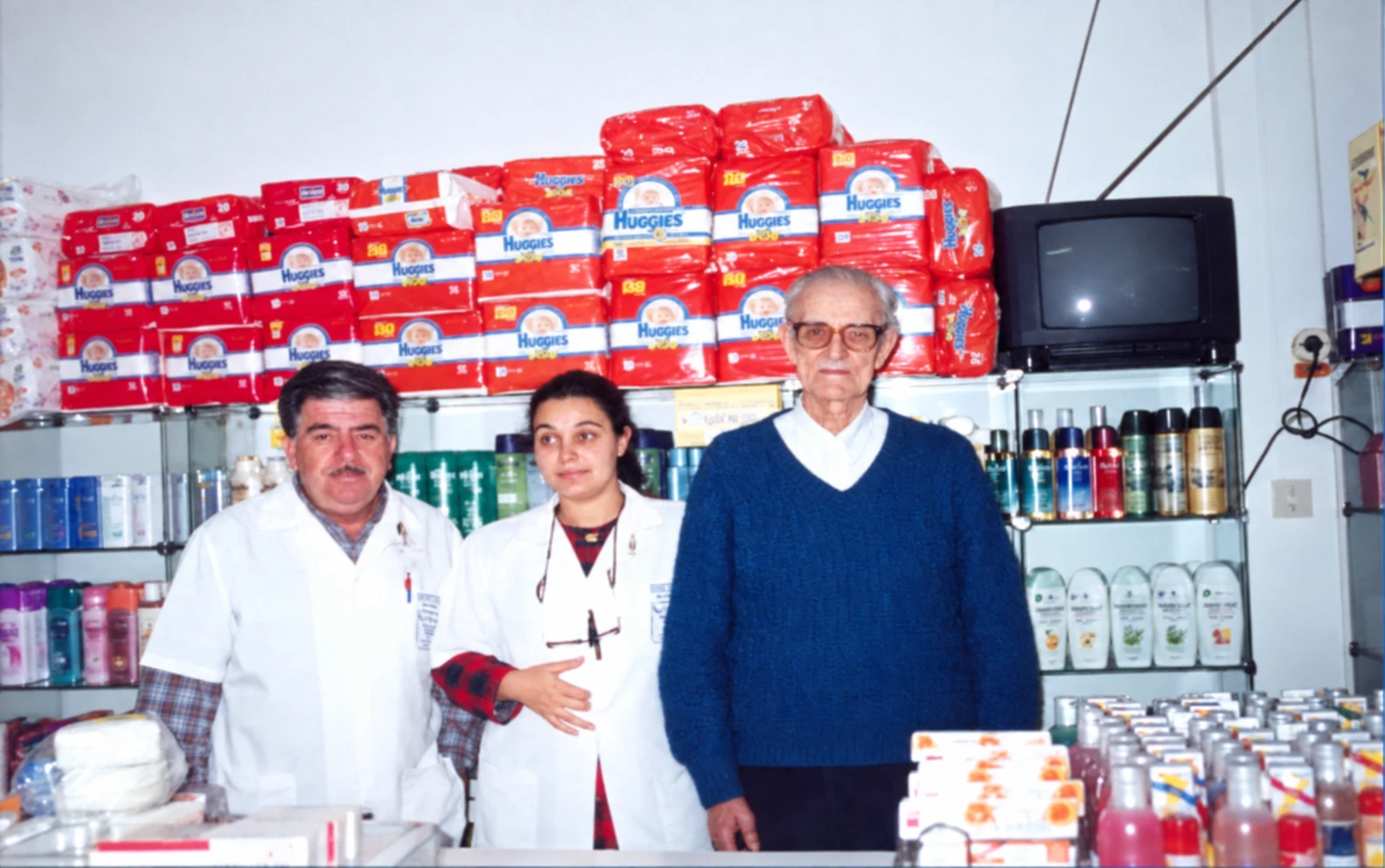 Equipe da Fleming no balcão de uma loja nos anos 1990, com pacotes de fraldas ao fundo